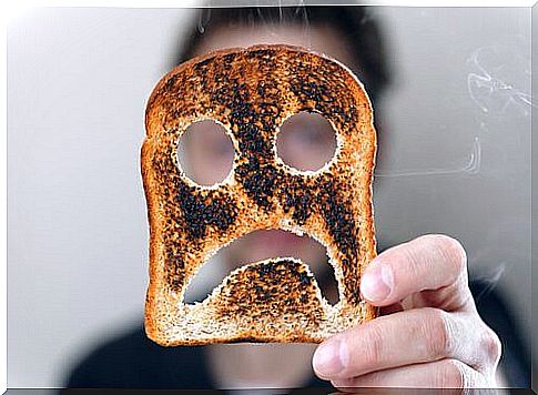 Person holding a piece of toast bread with a sour smiley