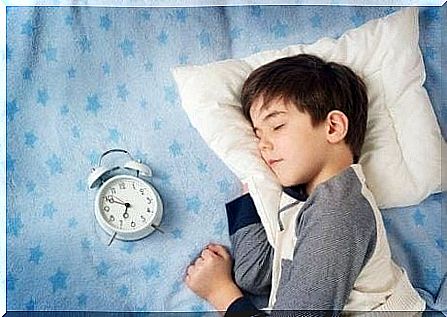 Boy sleeping with a clock next to it