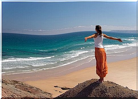 Woman standing on a hill by the beach