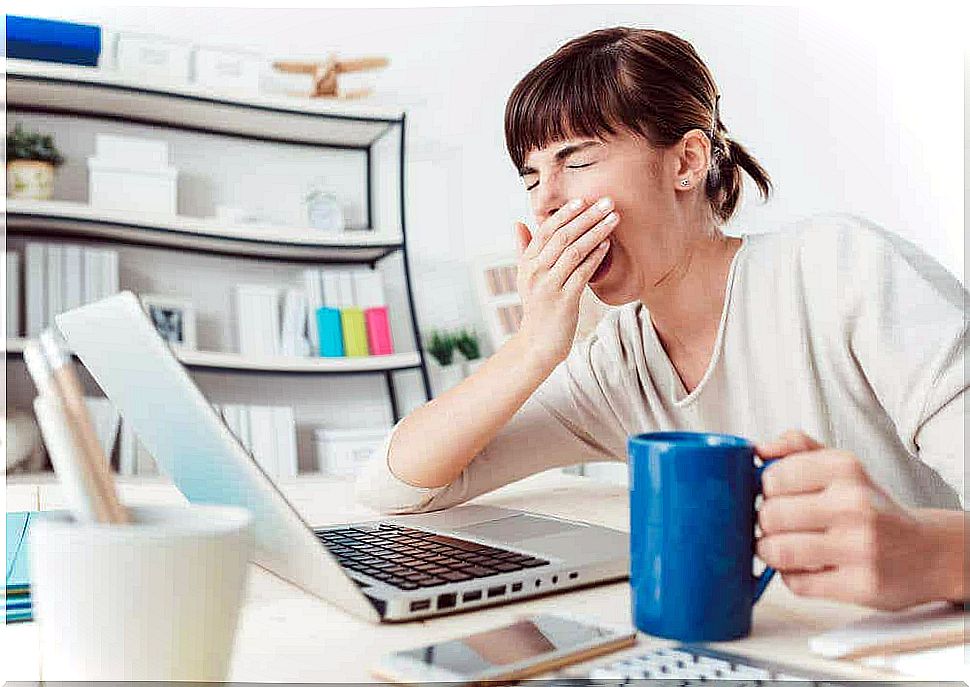 A woman yawns at a computer