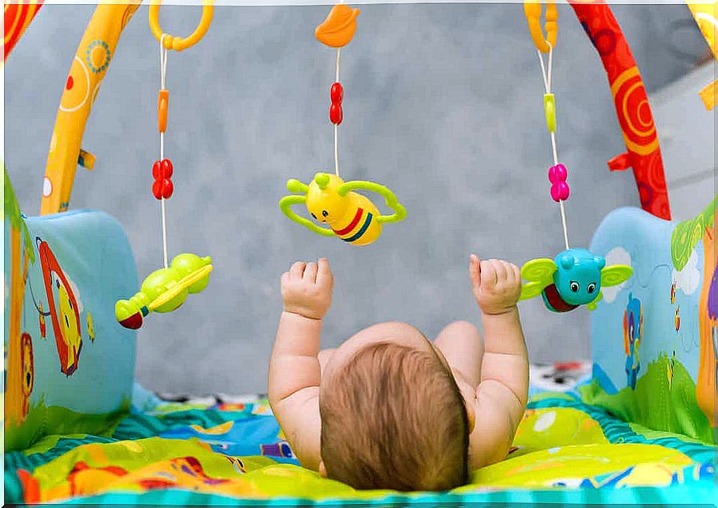 A child lying on his back playing on an activity blanket